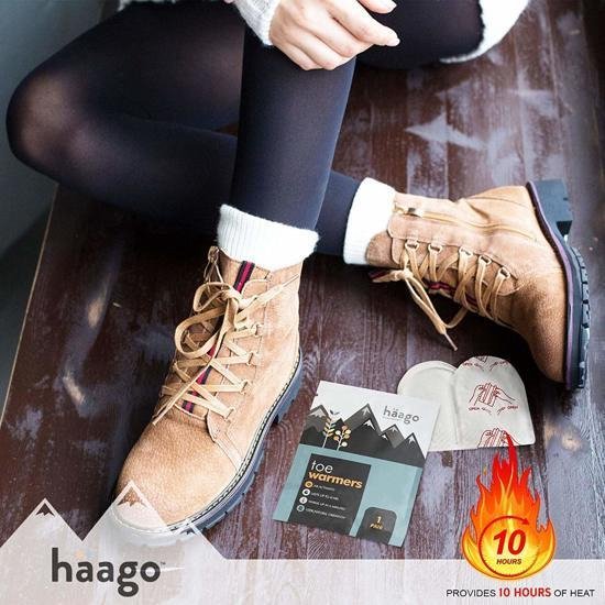 Een vrouw in een winterjas en laarzen, met een Häago teenthermowarmers verpakking en twee losse warmers op de grond.