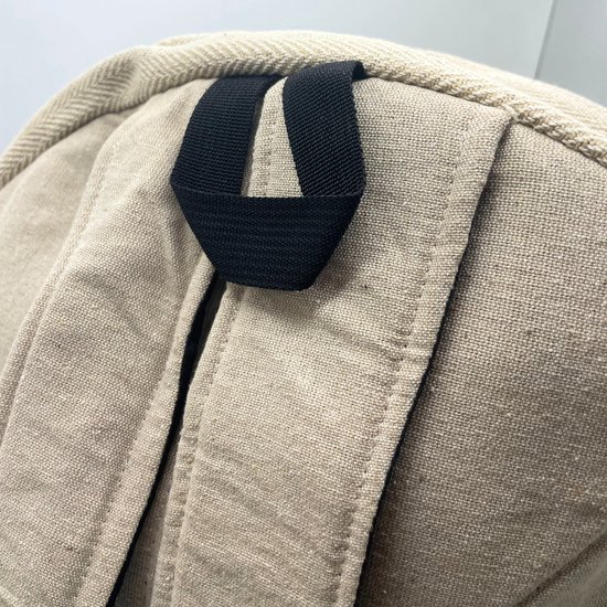Détail du haut d'un sac à dos beige avec une boucle noire et des coutures cousues.
