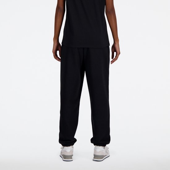 Zicht op de achterkant van een zwarte New Balance joggingbroek met witte sneakers.
