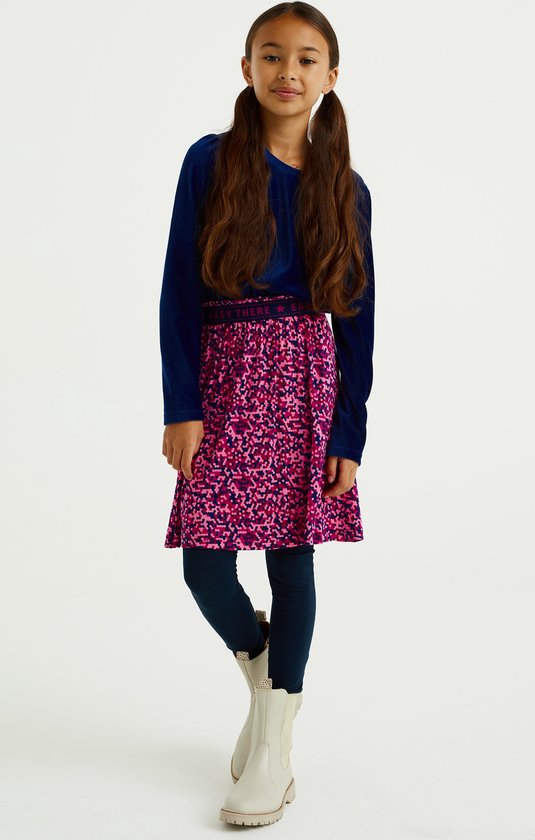 Meisje in marineblauwe coltrui, rok met roze en paarse print en donkerblauwe legging.