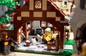 LEGO figuurtje met een lepeltje in een keuken met een witte kat en een geit.