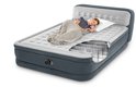 Een vrouw slaapt op een grijs Intex luchtbed met witte hoofdbord en matras.