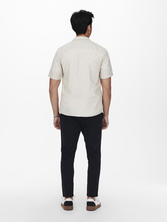 Man van achteren gezien, met een beige linnen mix overhemd met korte mouwen en een donkerblauwe broek.