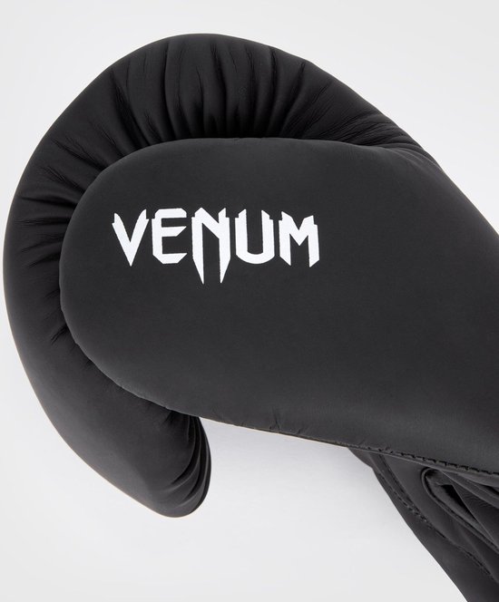Zwarte Venum bokshandschoen met wit logo, op een witte achtergrond.