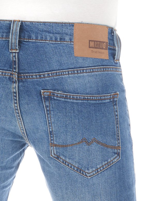 Achterkant van een blauwe Mustang jeans, bootcut fit, met een bruin leren label 'Mustang True Denim' en gestikte achterzakken.