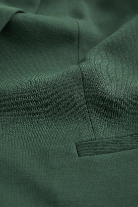 Gedetailleerde textuur van een donkergroene blazer, met naden en een paspelzak.