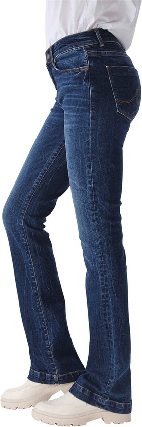 Donkerblauwe LTB Jeans Fallon flared jeans met een 'Morna Undamaged Wash'. Model draagt de jeans met een witte top en crèmekleurige schoenen.