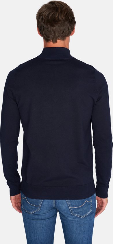 Achterkant van man in donkerblauwe trui met rits tot de borst en jeans.