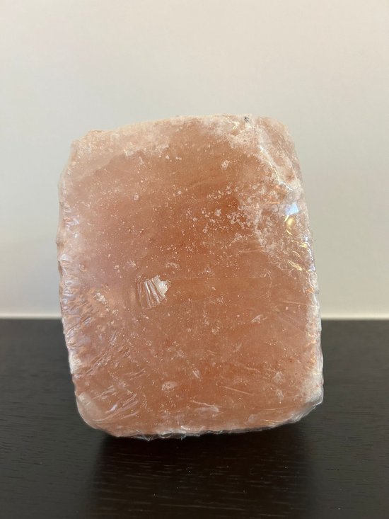 Roze Himalayazout liksteen in plasticfolie verpakt.