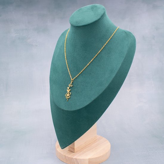 Gouden ketting met een bloem- en takjeshanger, tentoongesteld op een groene buste.