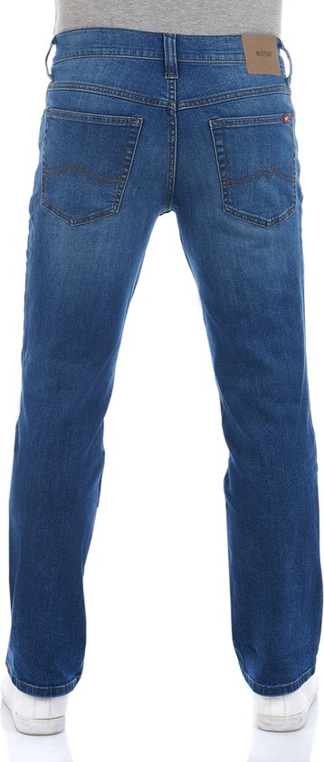 Achterkant van man in blauwe Mustang spijkerbroek, grijs T-shirt en witte sneakers.