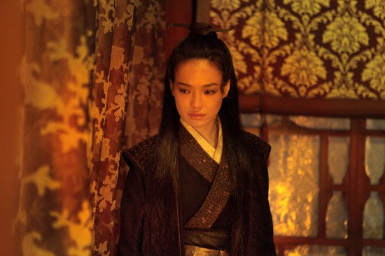 Shu Qi in een donker traditioneel kostuum met gedetailleerde randen en haar opgestoken.