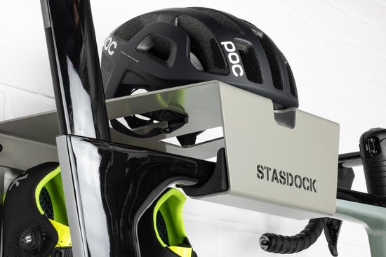 Zwart POC racefietshelm op een zilverkleurig Stasdock-rek, met een zwarte racefietsschoen met limegroene accenten.