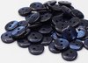Un tas de boutons bleu foncé à 2 trous, brillants avec des reflets irisés.