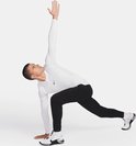 Man met witte lange mouwen shirt en zwarte sportbroek in een dynamische pose.