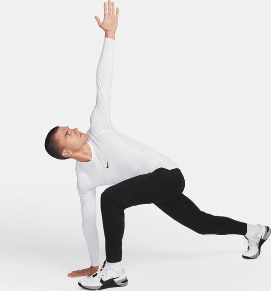 Man met witte lange mouwen shirt en zwarte sportbroek in een dynamische pose.
