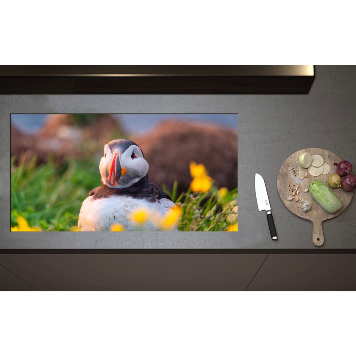 Inductieplaat Beschermer - Aankijkende Papegaaiduiker Vogel in Landschap met Gele Bloemetjes - 95x50 cm - 2 mm Dik - Inductie Beschermer - Bescherming Inductiekookplaat - Kookplaat Beschermer van Zwart Vinyl