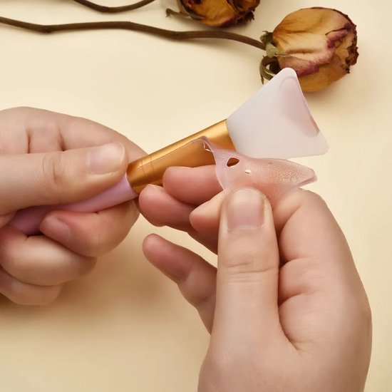 Mains tenant une spatule réutilisable en silicone rose avec une partie orange près de la lame.