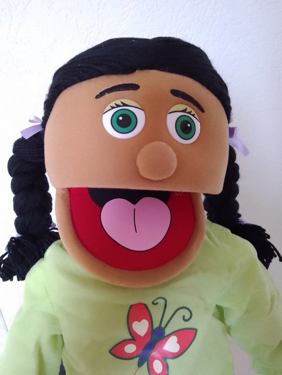 Buikspreekpop met bruine huid, zwarte vlechten, groen ogen en een open mond met rode binnenkant en roze tong.