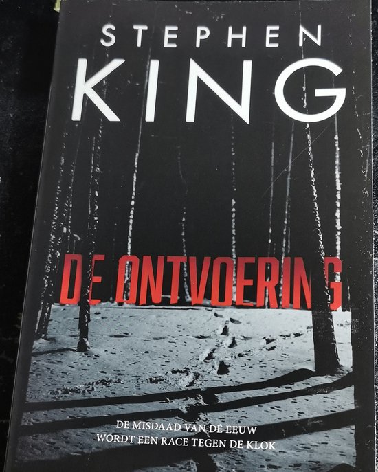 Boekcover van Stephen Kings 'De Ontvoering' met een winterse bosweg en de titel in rode letters.