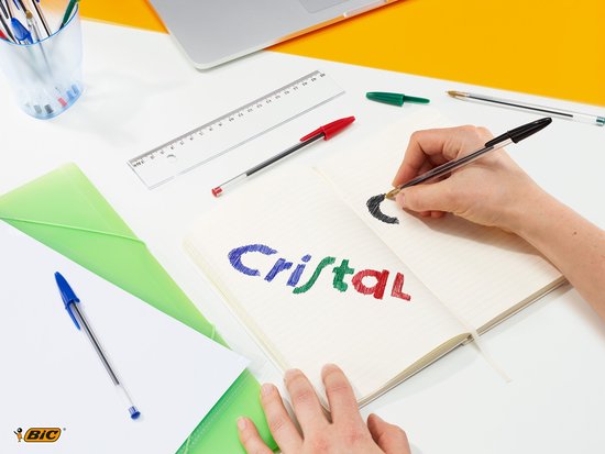 Bovenaanzicht van een bureau met een notitieboekje, liniaal en Bic pennen.