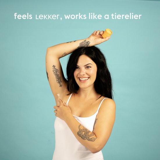 Vrouw met tatoeages brengt Lekker deodorant aan onder haar arm. De verpakking is geel.