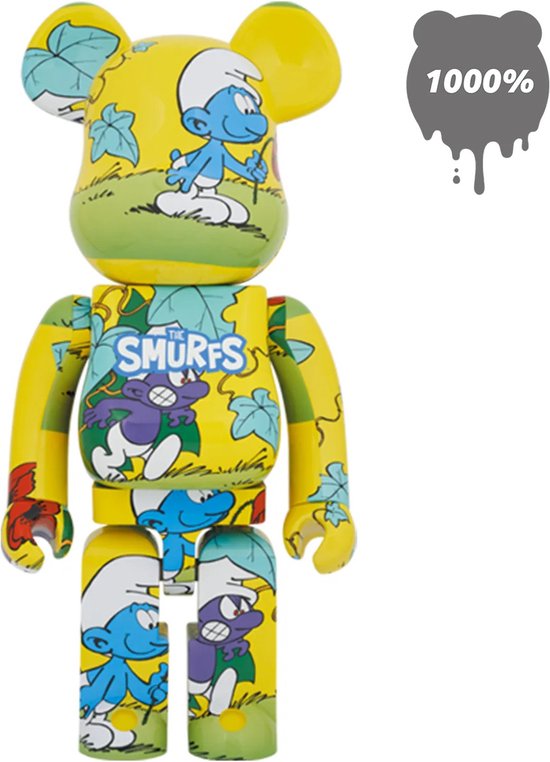 Bearbrick 1000% met opdruk van De Smurfen en Gargamel op een gele achtergrond met bladeren en gras. De tekst 'The Smurfs' is zichtbaar.