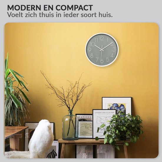 Moderne grijze wandklok met witte wijzers en cijfers, hangend aan een gele muur met diverse decoraties.