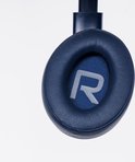 Detailopname van de donkerblauwe oorcup van een PowerLocus koptelefoon met een zilveren 'R' logo.