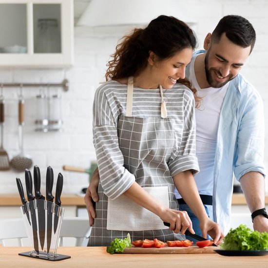 Man en vrouw snijden samen tomaten, keukenmes in blok op tafel