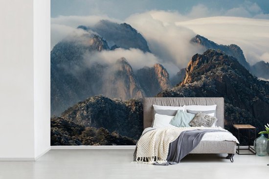 Behang - Fotobehang - Dik pak mist hangt over de rotsige heuvels - Breedte  420 cm x... | bol.com