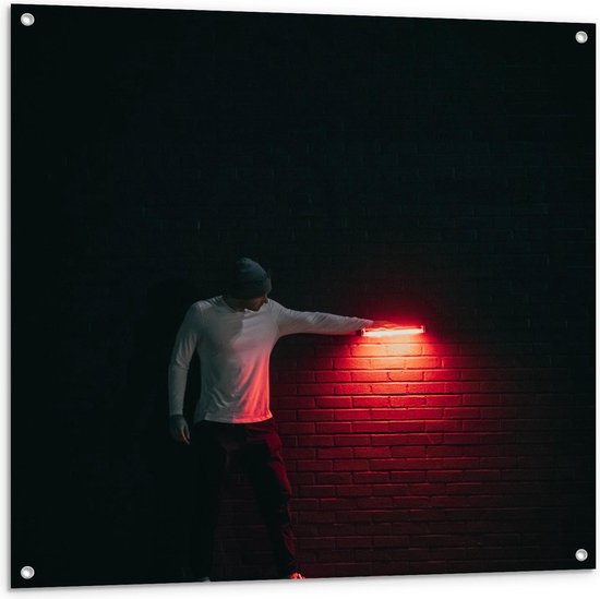 Tuinposter – Man met Rode Lamp tegen Muur - 100x100cm Foto op Tuinposter  (wanddecoratie voor buiten en binnen)