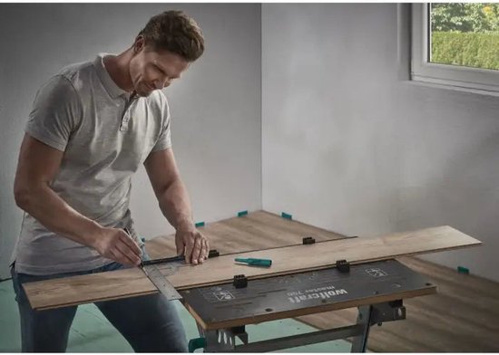 Een man in een grijs T-shirt gebruikt een wolfcraft winkelhaak en markeert een houten vloerplank.