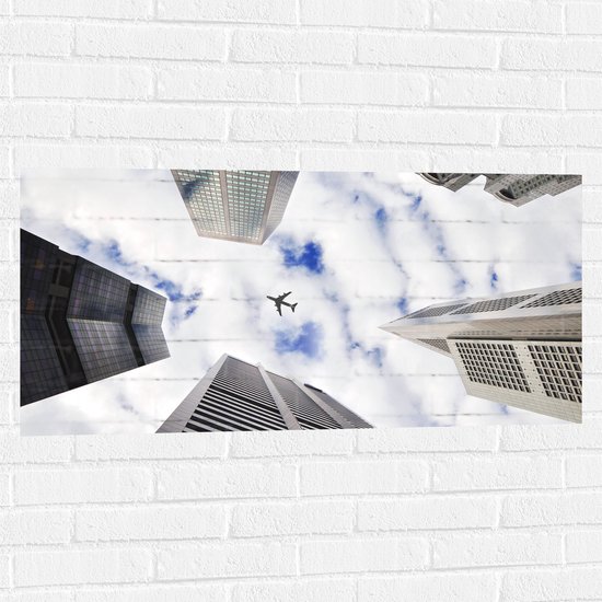 Muursticker - Vliegtuig tussen Gebouwen in de Lucht - 100x50 cm Foto op Muursticker