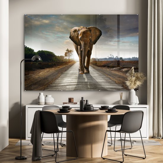 Un éléphant marche sur une route au coucher du soleil, affiché dans une salle à manger.