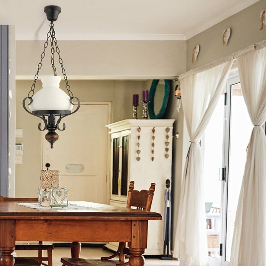 Hanglamp met melkglazen kap en zwarte ketting, hangend boven een houten tafel.