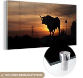 MuchoWow® Glasschilderij 80x40 cm - Schilderij acrylglas - Silhouet van een stier bij zonsondergang - Foto op glas - Schilderijen