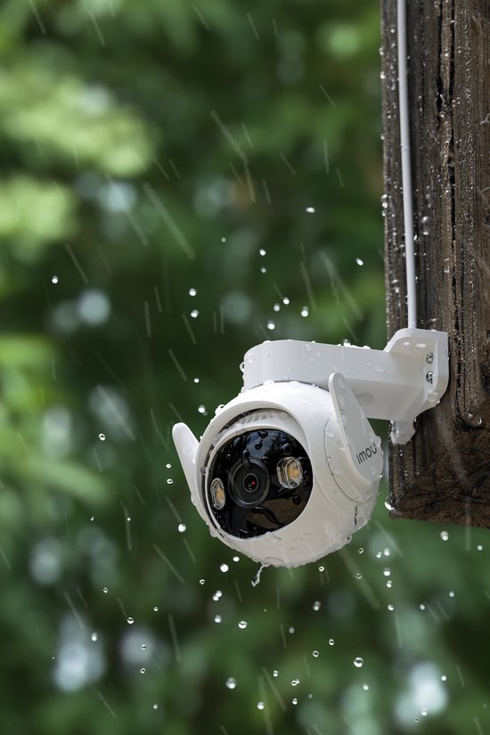 Witte Imou beveiligingscamera met zwenkarm, gemonteerd op een houten paal, met regendruppels op de lens.