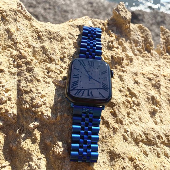 Blauw metalen Jubilee horlogebandje met Romeinse cijfers op de wijzerplaat, op zand.