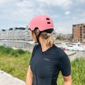 Femme aux cheveux blonds portant un casque PRO SPORT LIGHTS rose et un maillot noir.
