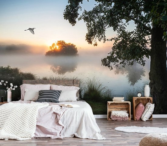 Chambre décorée d'une fresque représentant un lever de soleil serein sur un lac brumeux, avec la silhouette d'une île et un oiseau dans le ciel.