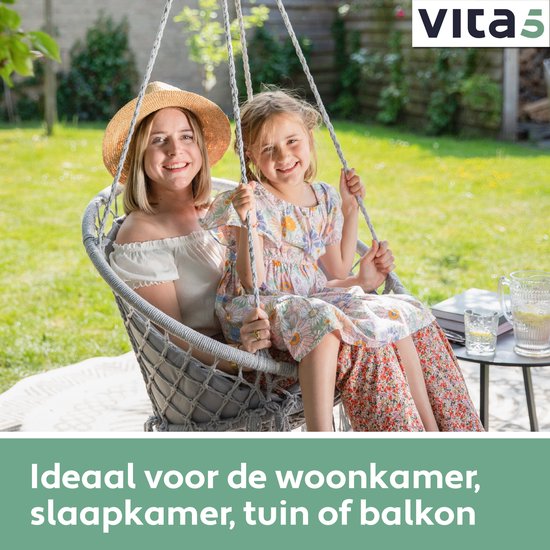 Grijze macramé hangstoel met franjes, waarin een vrouw en een meisje met zomerjurkjes zitten.