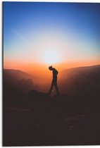 WallClassics - Dibond - Silhouet Persoon tussen de Bergen bij Zonsondergang - 50x75 cm Foto op Aluminium (Met Ophangsysteem)