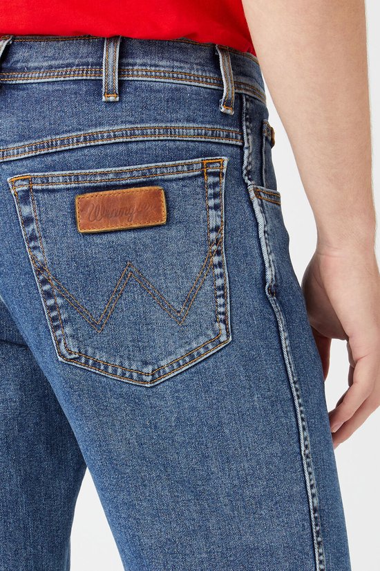 Close-up van de achterkant van een blauwe Wrangler spijkerbroek met bruin leren logo.
