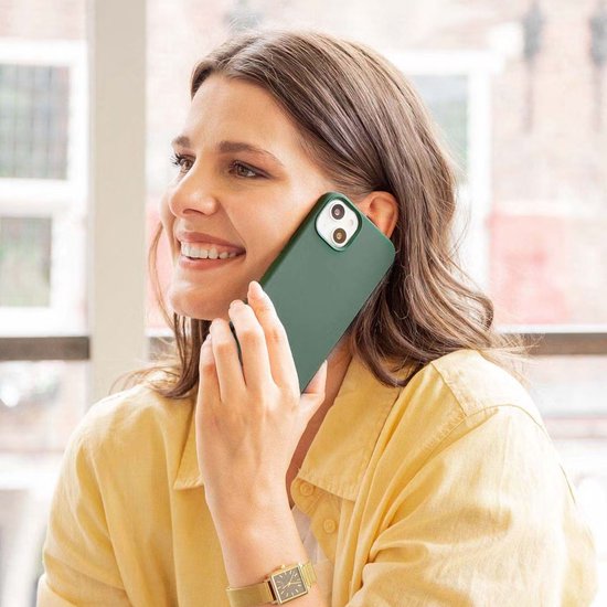 Vrouw met een groen telefoonhoesje aan de telefoon.