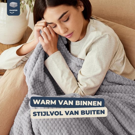Vrouw omarmt een zachte, grijze deken met wafelstructuur, genietend van de warmte.