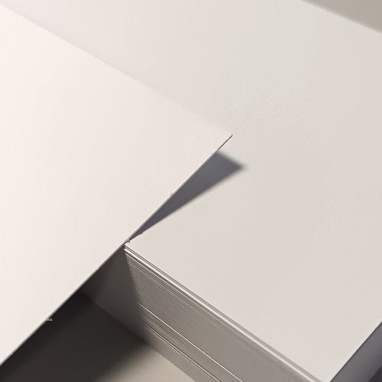 Close-up van de randen van gestapelde witte kaarten, waarvan één is verschoven.