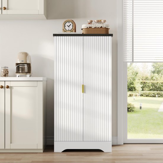Gesloten wit opbergmeubel met een geribbelde textuur en gouden handgrepen, naast een aanrecht in een lichte keuken.