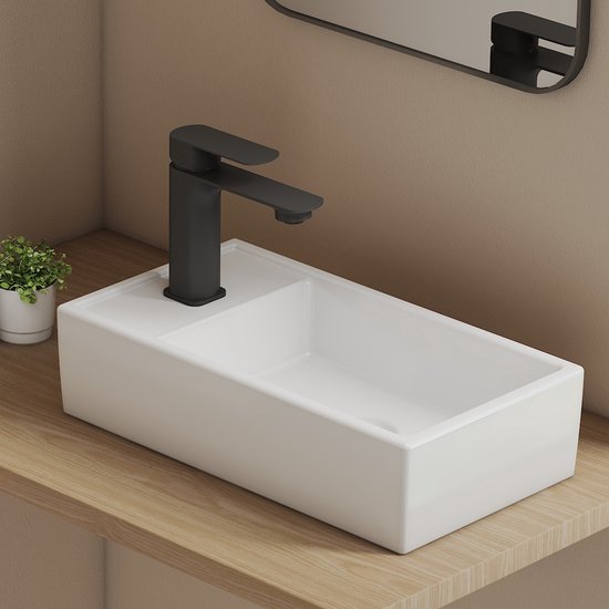 Lavabo blanc rectangulaire avec une zone surélevée derrière le robinet.