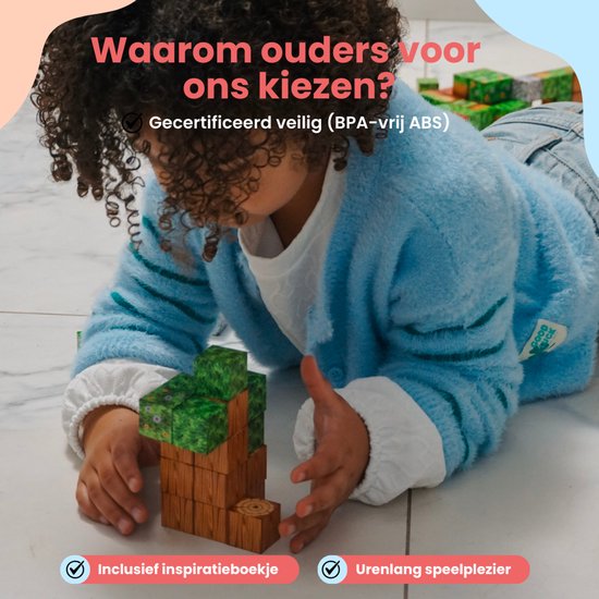 Een jong kind met krullend haar, gekleed in een blauwe trui, speelt met magnetische blokken op de vloer. Ze bouwt een toren van houten en grasblokken.